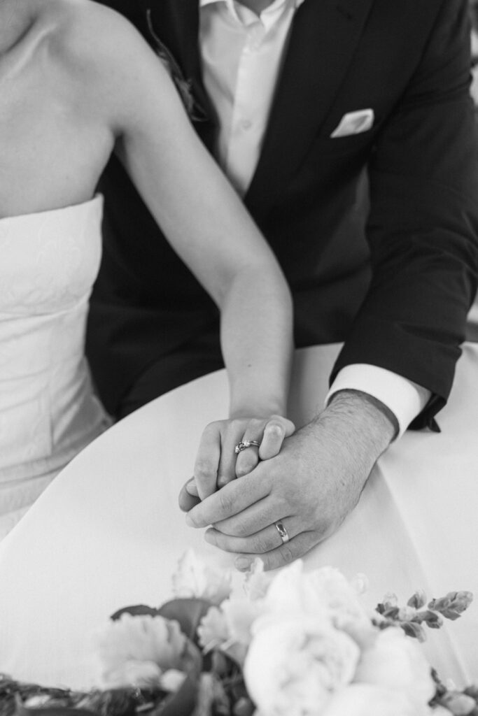 closeup of wedding rings and bride and groom holding hands