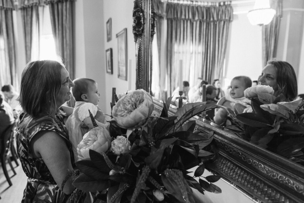 mother of the bride playing with a baby in the reflection of a mirror in the dining room