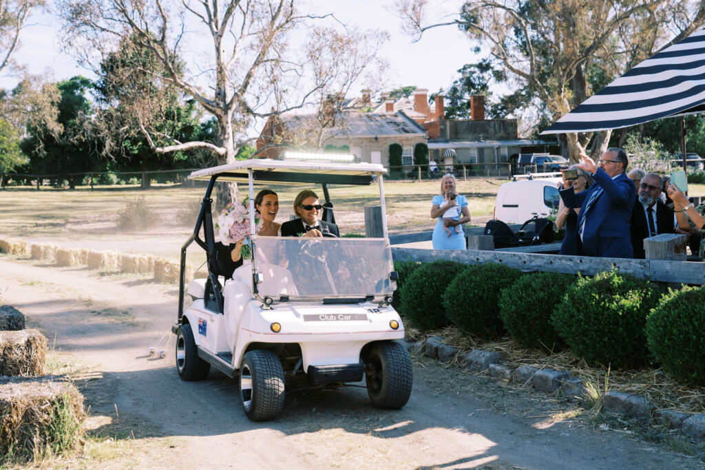 bride and groom riding to their wedding reception together in a golf cart