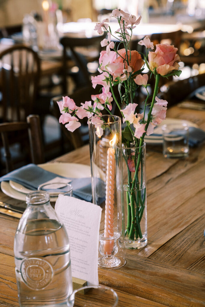 closeup décor photos of pink flowers, dinner menu and candles for a wedding reception 