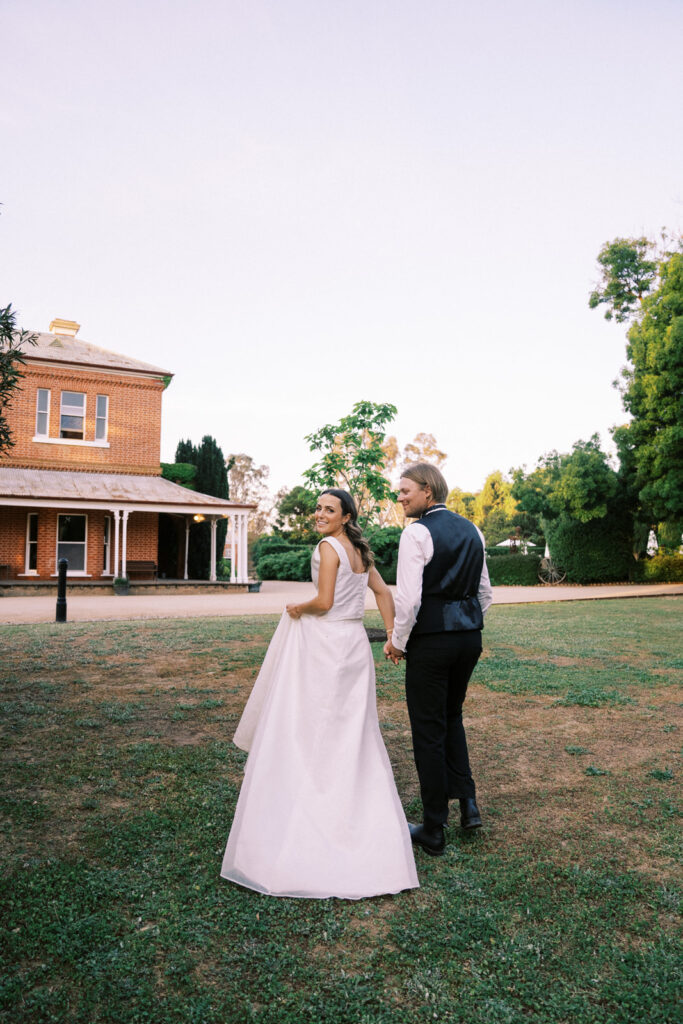 bride and groom walking together toward the main house of ravenswood homestead