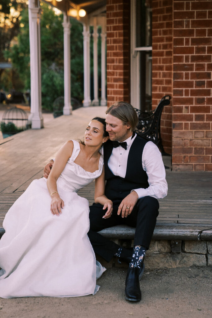 bride and groom sitting together on the deck of the main house at ravenswood homestead