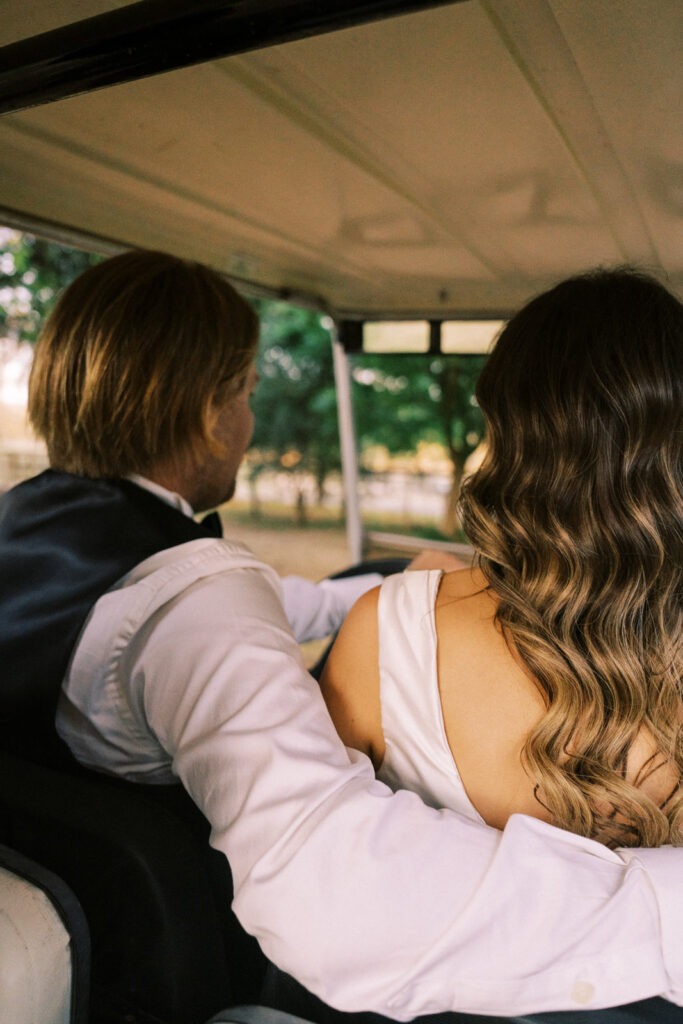 bride and groom driving together in a golf cart