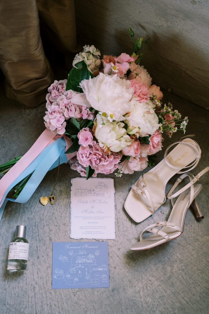 detail photo of the brides shoes, invitation, flowers, perfume and locket