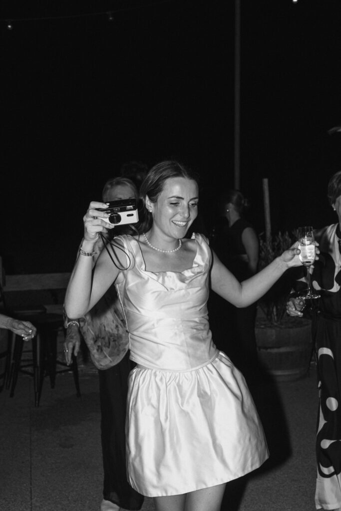 bride holding a film camera on the dancefloor