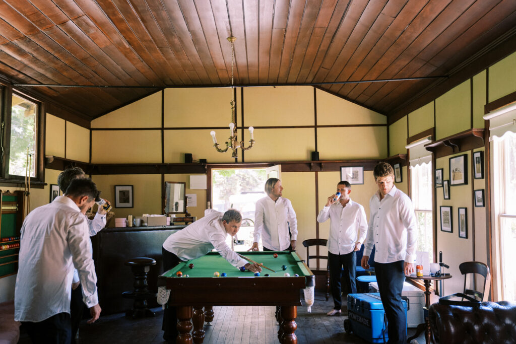 the groom and groomsman playing pool in the rumpus room 