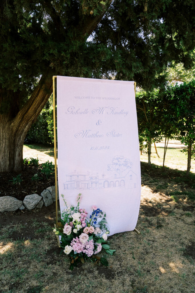 a fabric welcome sign blowing in the wind designed by the bride