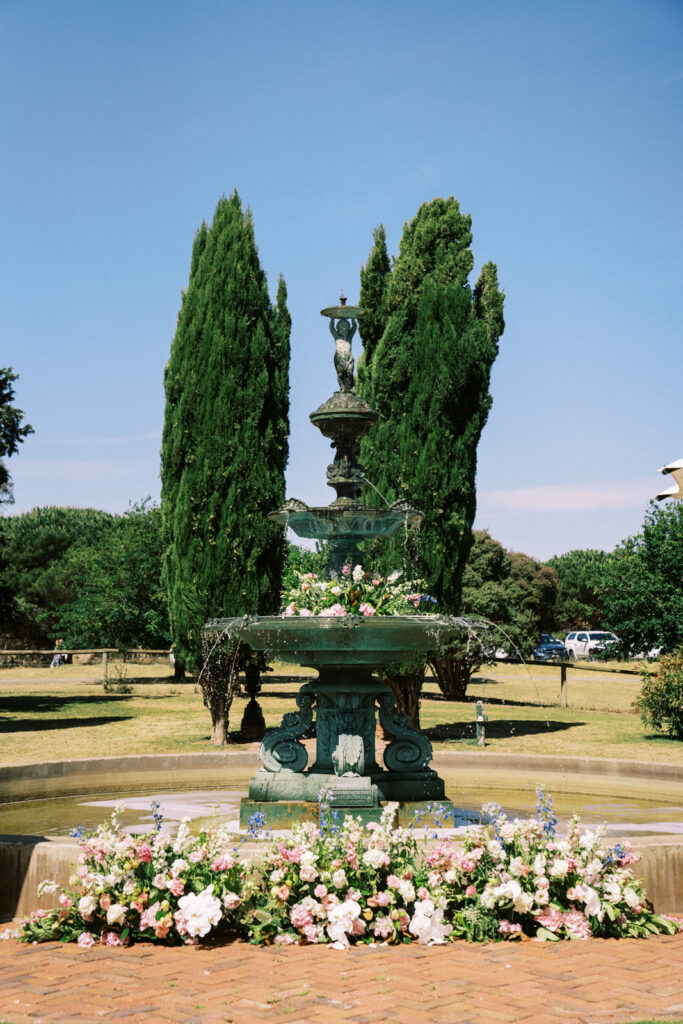 wedding flowers in front of the fountain and in the fountain in the garden ceremony